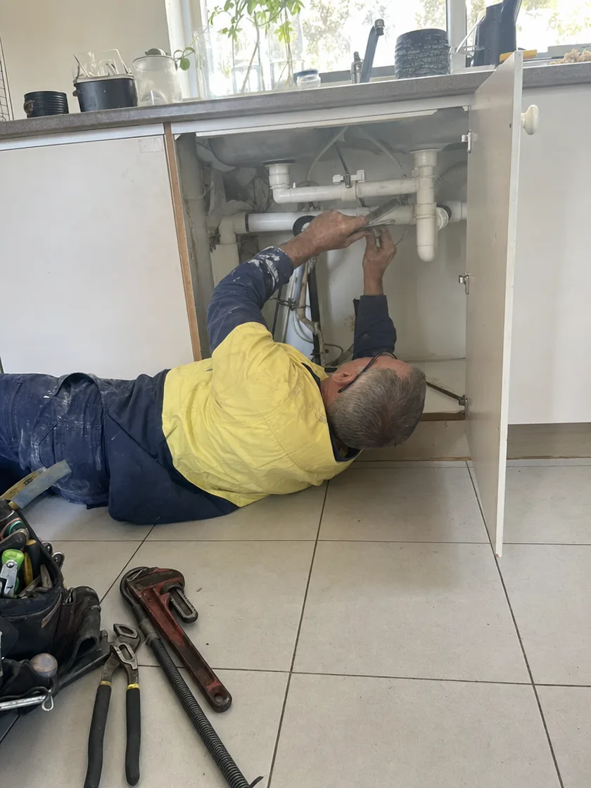 Plumber working under a kitchen sink